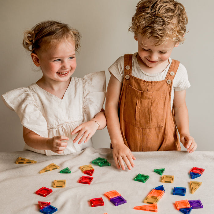 Twee lachende kinderen met magnetische tegels aan tafel
